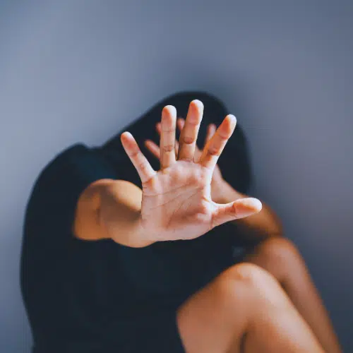 a woman holder her hand up to protect herself